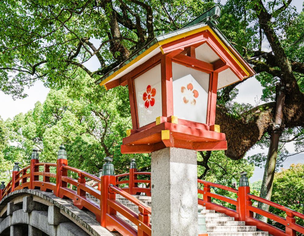 Vermilion arched bridge and a stone lantern with the plum-blossom crest at Dazaifu Tenmangu